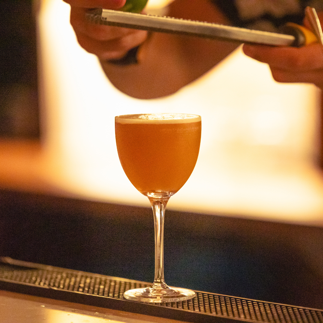 Island Echo Cocktail in a glass with a blurred bar setting