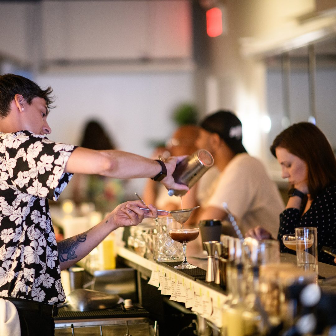 A bartender pouring for guests at the counter at No More Cafe