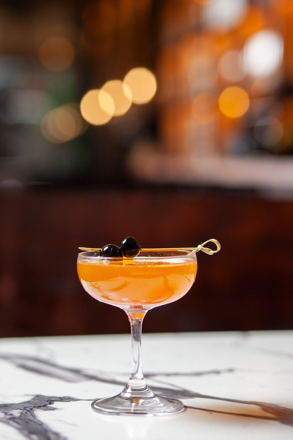 A cocktail in a coupe with cherries at No More Cafe